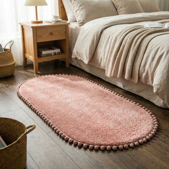 Plush oval pompom bath rug. Soft, absorbent, and non-slip, ideal for modern bathroom decor and comfort.