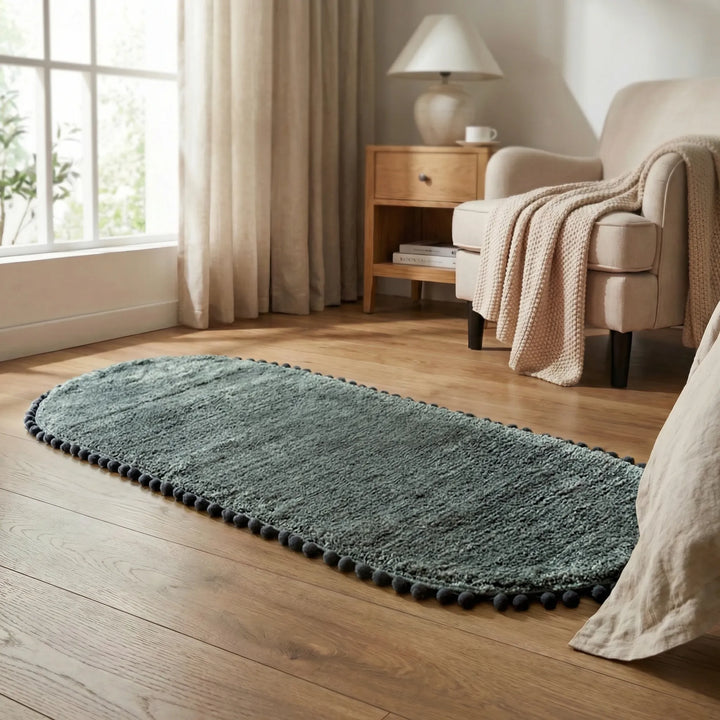 Comfortable oval pompom bath rug, plush and absorbent. Modern non-slip bathroom mat for stylish home decor.