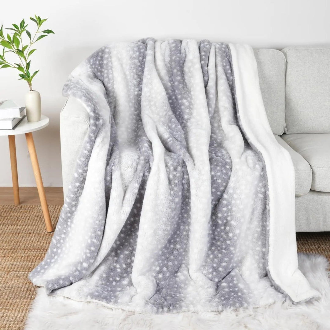 Hand touching the ultra-soft plush faux fur deer blanket, a cozy reversible throw for luxurious warmth.