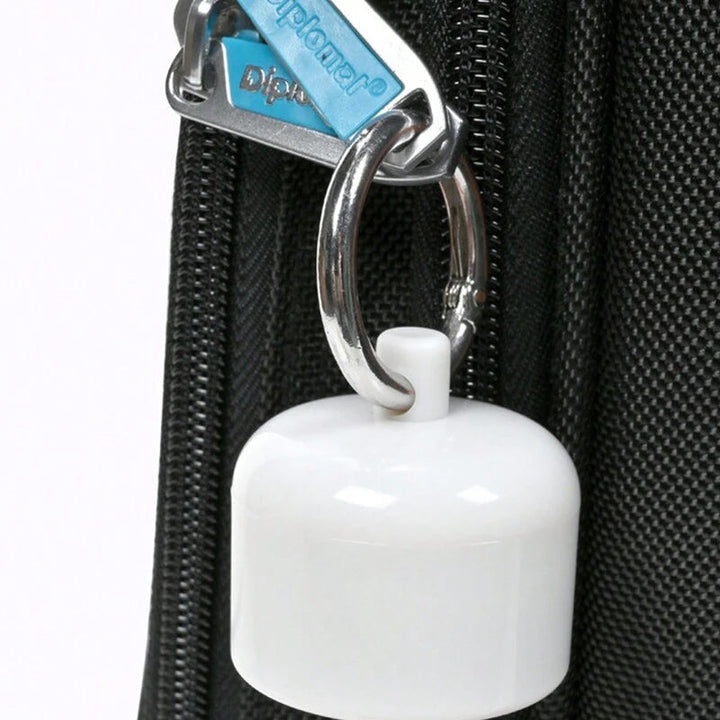 Close-up of a silver keychain pill holder, displaying its secure screw-top closure