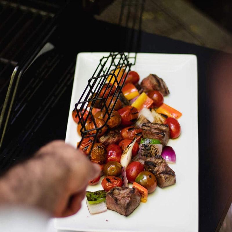 Grill kabob basket with skewered meats and vegetables cooking over open flame, nonstick for easy cleaning.