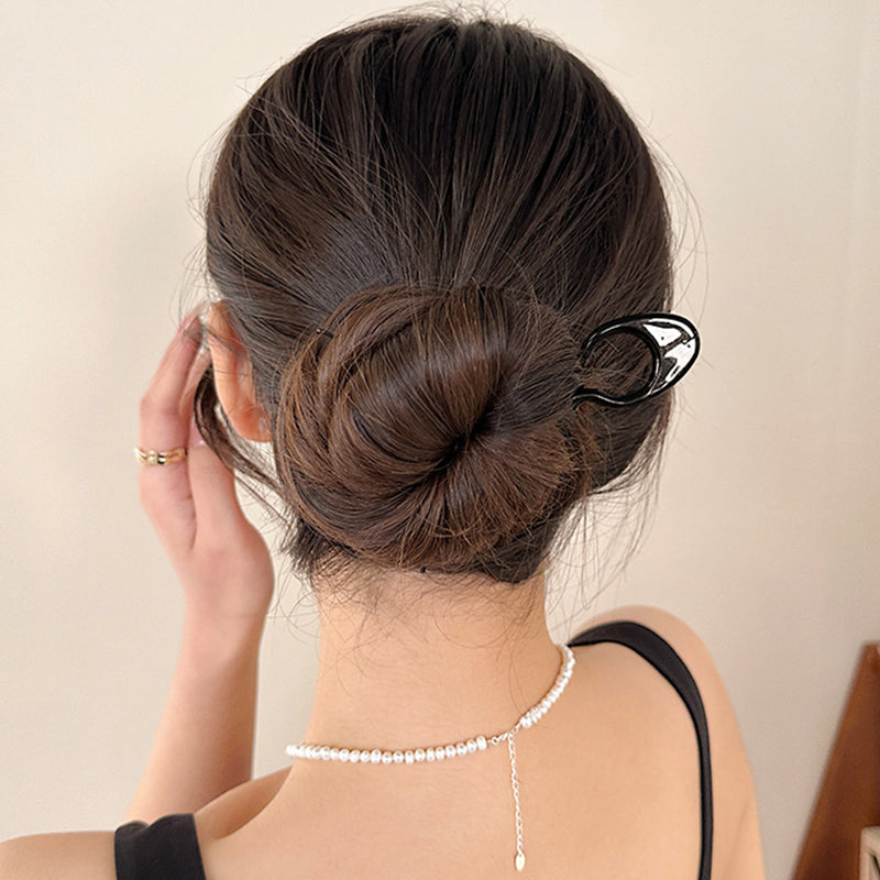 Side view of a woman with an elegant updo, secured by the discreet black hair pins.