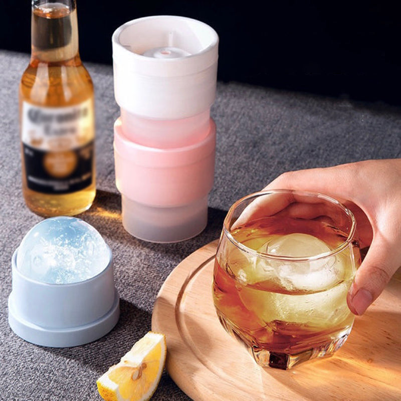Hand holding a clear, perfectly round sphere ice ball made from the stackable mold, great for drinks.
