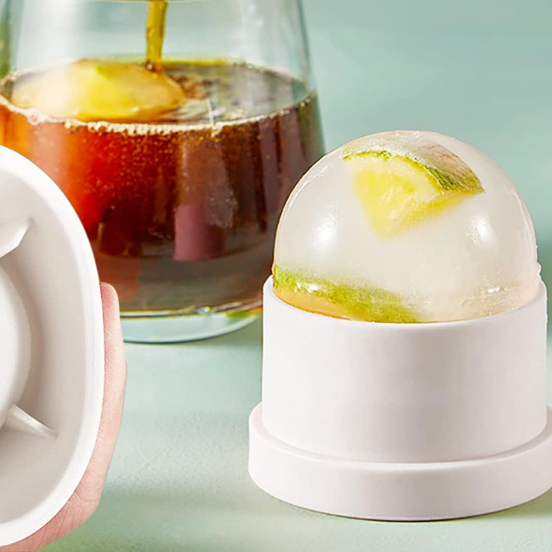 Stackable sphere ice ball molds next to a glass of iced cocktail, highlighting their use as a drink accessory.