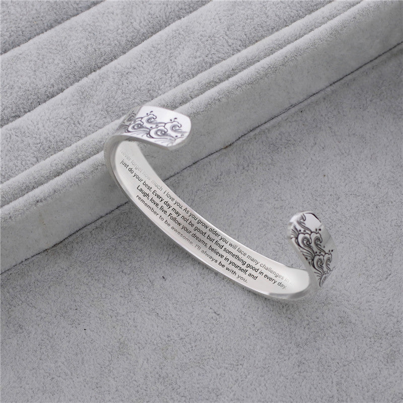 Granddaughter love message cuff bracelet on a teenage girl's wrist, close-up, worn on arm