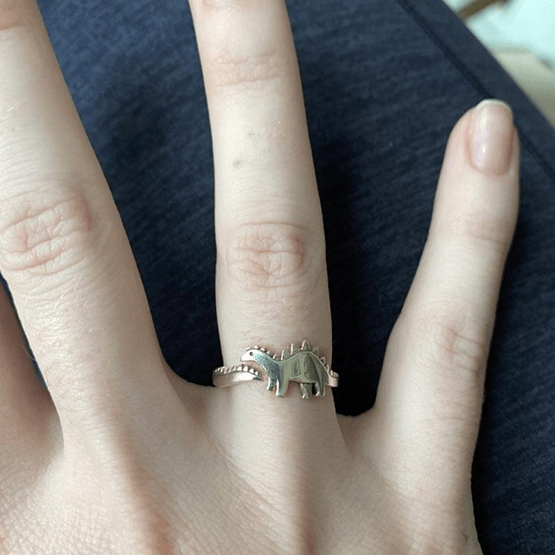 Close-up of an adjustable dinosaur ring, silver-toned metal, charming animal jewelry for unisex wear