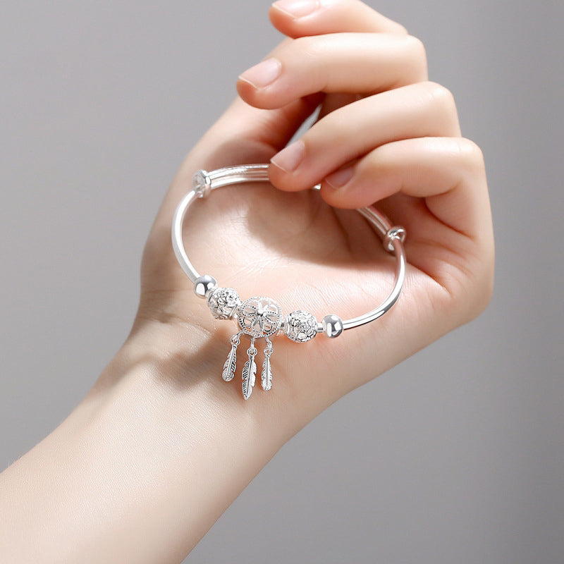Close-up of a dreamcatcher charm on a women's silver bracelet, adjustable, gift included