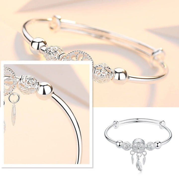 Hand modeling a womens silver dreamcatcher charm bracelet, adjustable for perfect fit, in gift box