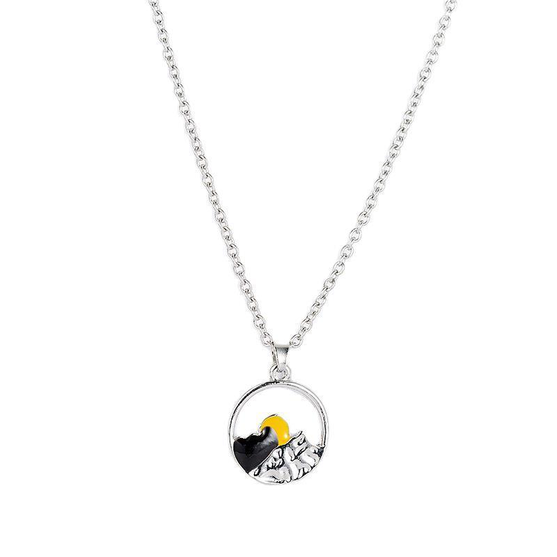 Close-up of the textured silver mountain landscape on a unisex couple's necklace.