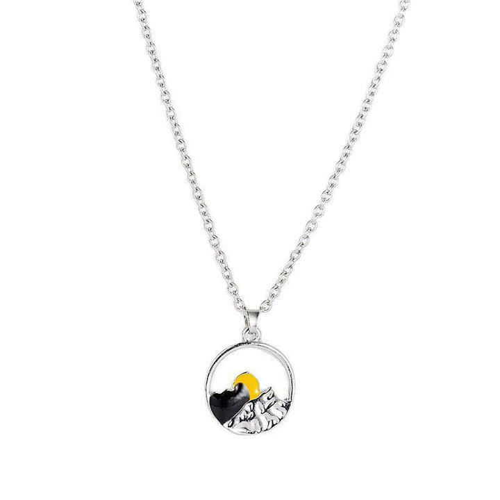 Close-up of the textured silver mountain landscape on a unisex couple's necklace.