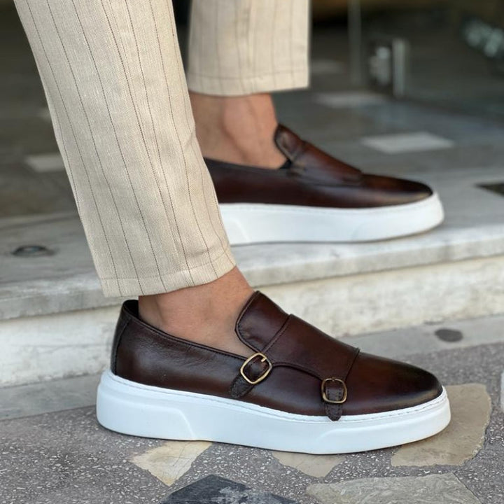 Sleek men's black leather lace-free sneakers with elegant buckle details, ideal for modern casual style.