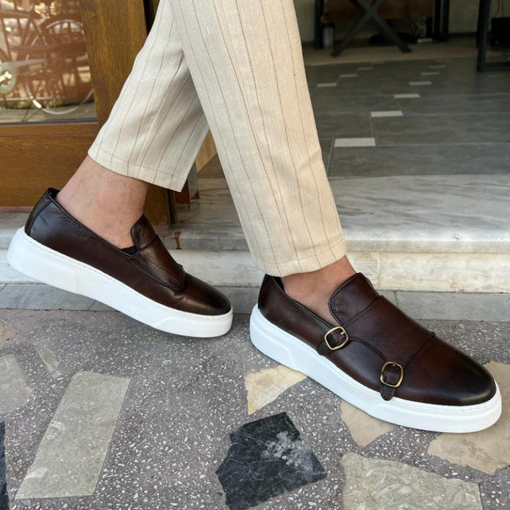 Close-up of a modern men's leather sneaker, showcasing the elegant buckle detail and smooth finish.
