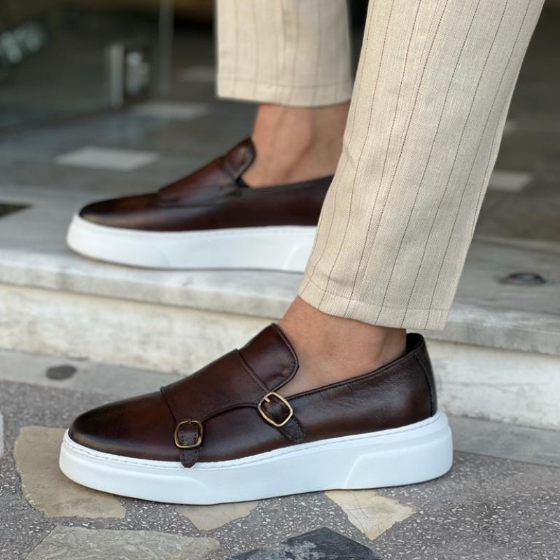 Pair of modern men's black leather lace-free buckle sneakers, offering sleek, comfortable everyday footwear.