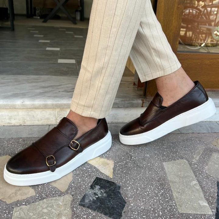 Versatile men's black leather slip-on sneakers with buckle straps, combining comfort with modern sleek style.