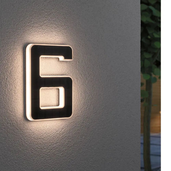 Weatherproof solar LED house number mounted on a wall, enhancing curb appeal.