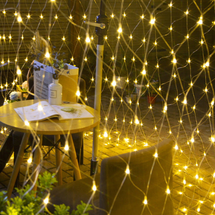 Solar powered mesh lights draped over a bush, creating a festive outdoor ambiance at night