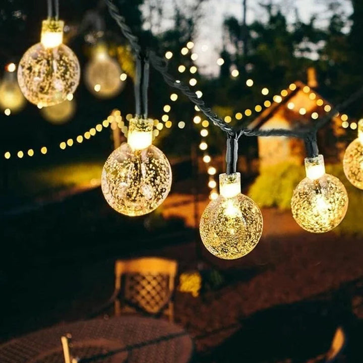 Close-up of waterproof LED string lights with a solar panel, ideal for garden and patio lighting