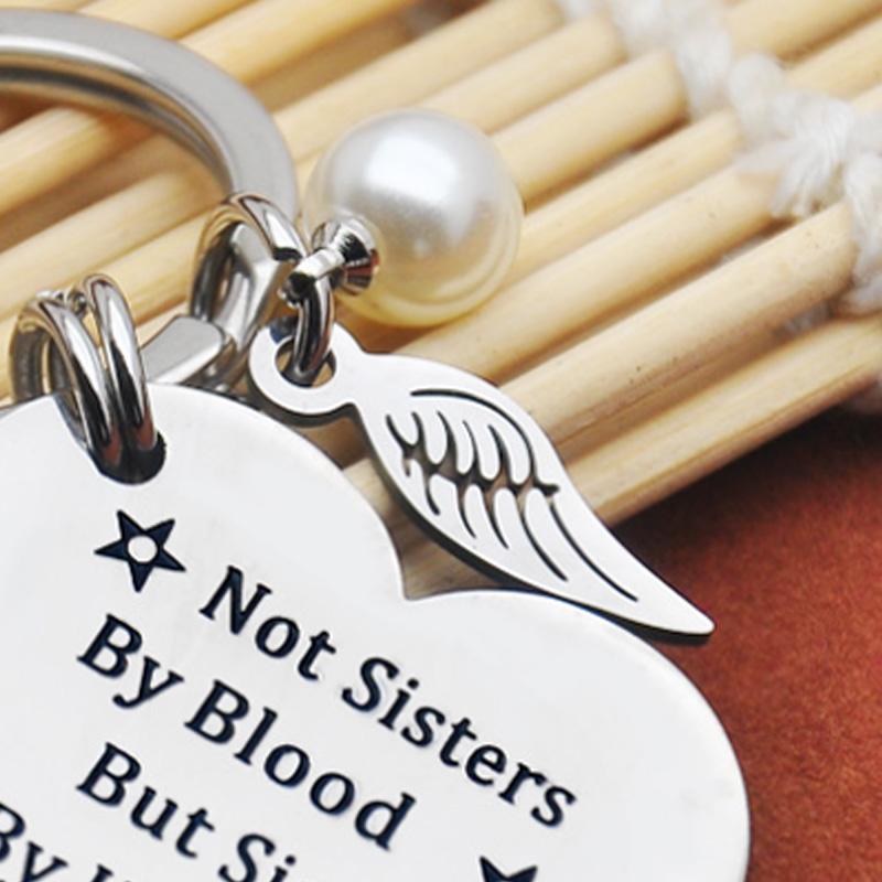 Close-up of a round stainless steel keychain, 'Sisterhood' text clearly visible, friendship accessory.