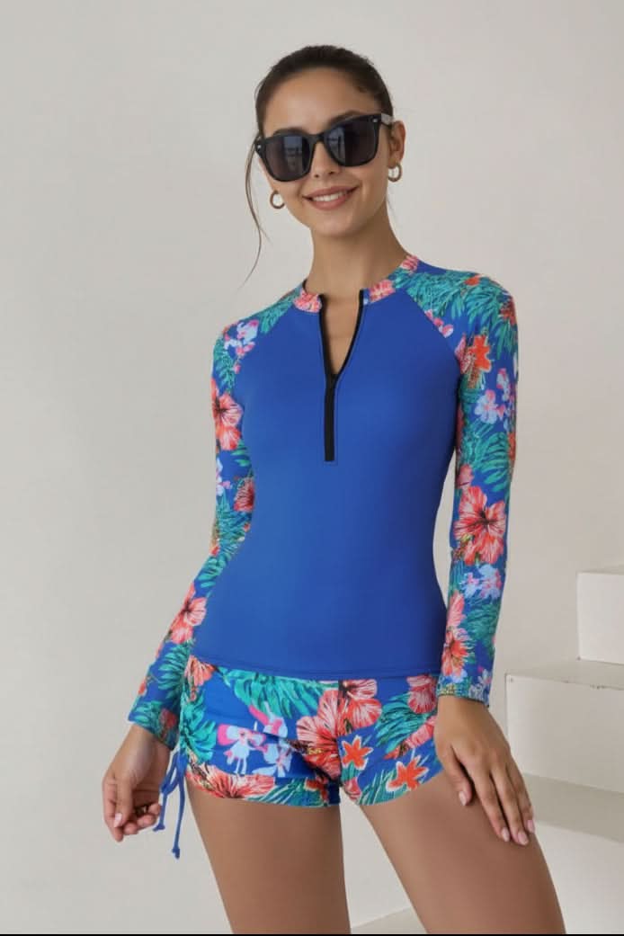 Model in a women's sporty long sleeve tropical rashguard swimsuit, perfect for active surf & beach days.