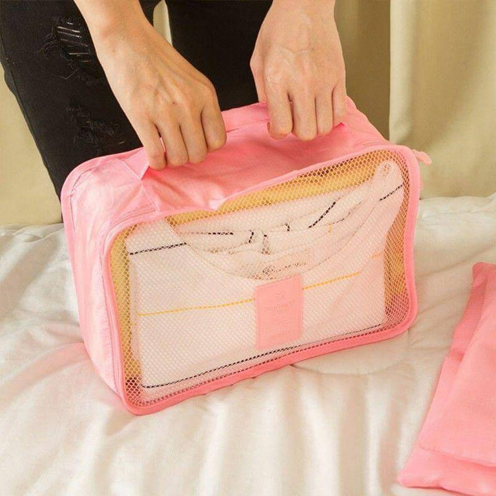 Hand holding a portable travel organizer cube. Easy to carry & fit into any travel bag.