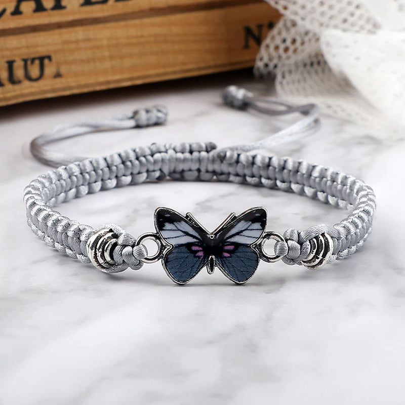 Multiple colorful adjustable cotton butterfly charm bracelets, stacked together.
