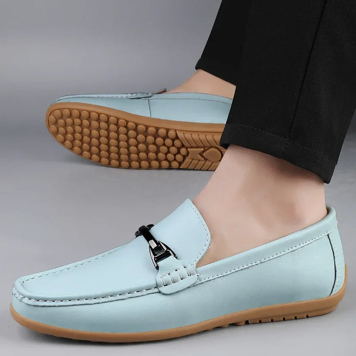 A stack of various colored unisex leather loafers, showcasing the range of available options.