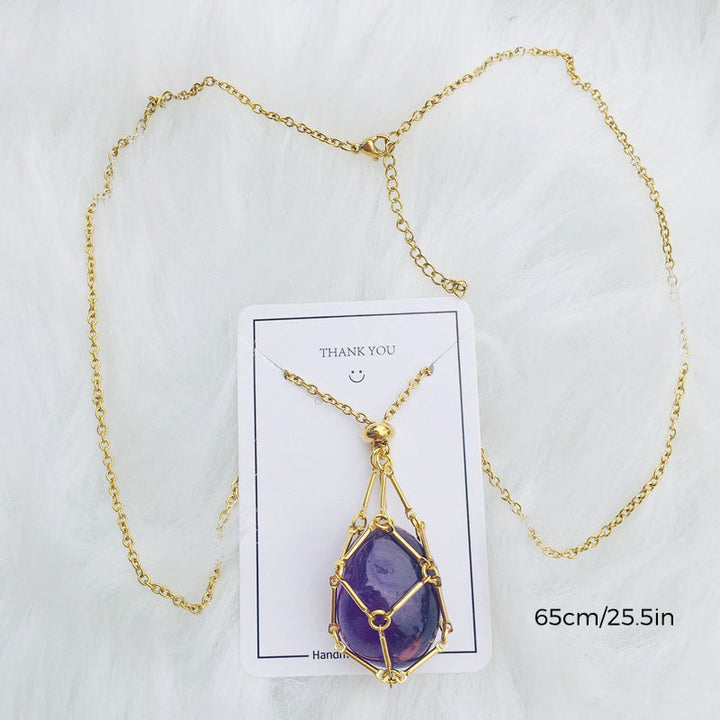 Empty silver crystal cage pendant necklace displayed on a wooden surface, earthy aesthetic