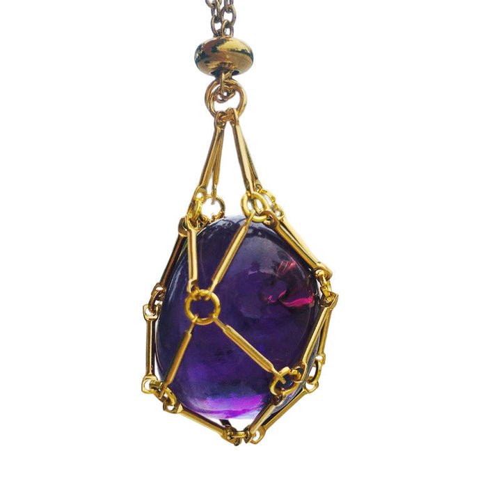 Crystal cage pendant necklace, unisex, beside a collection of healing stones, spiritual