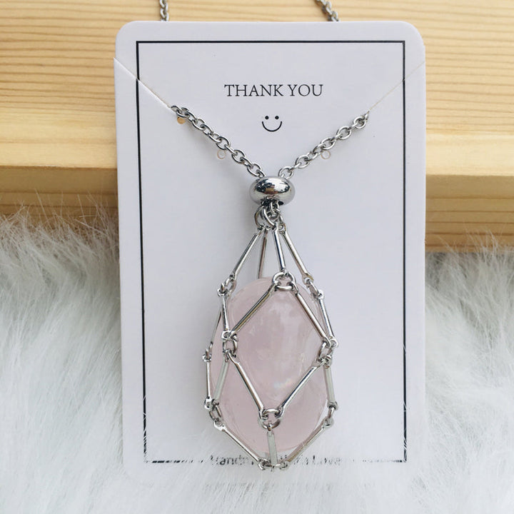 Hand holding a silver crystal cage pendant necklace, demonstrating scale and quality