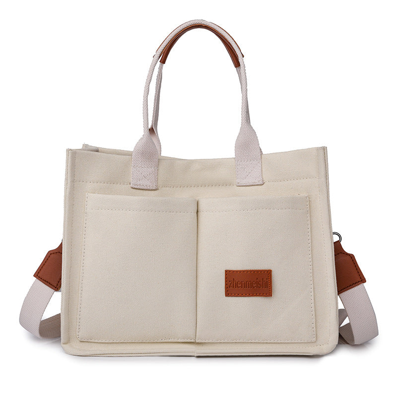 A neutral-toned canvas shoulder bag, a fashionable and durable accessory for all genders.