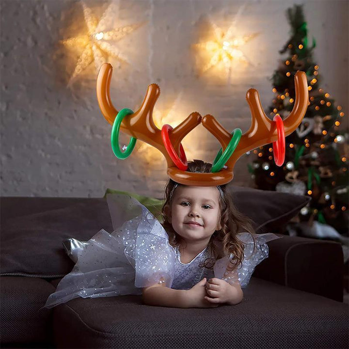 Group of friends laughing while playing inflatable antler ring toss at a Christmas gathering