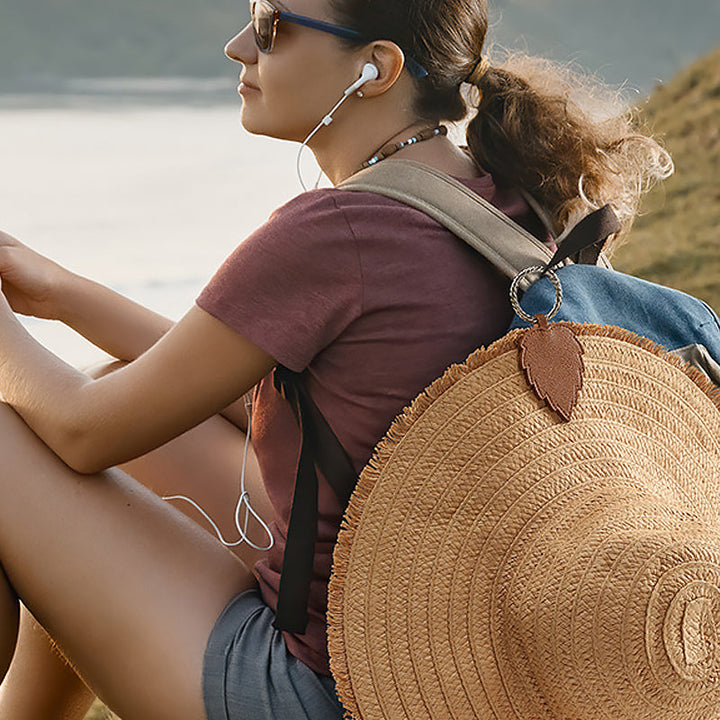 Unisex magnetic hat clip in black faux leather, attaches to bag for hands-free travel.