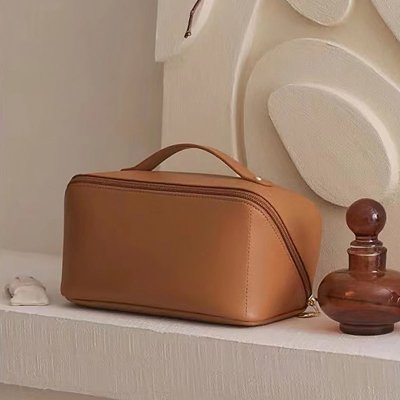 Hand holding a unisex PU leather cosmetic travel bag, showcasing its compact size and portability.