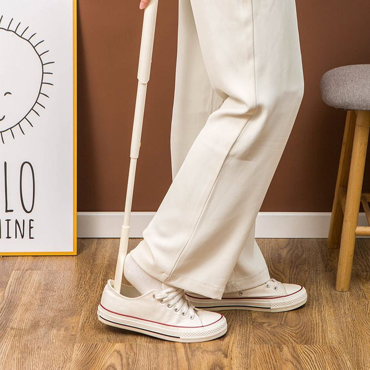 Telescopic shoe horn next to various footwear, highlighting its versatility as a daily aid