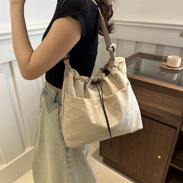 Side profile of a unisex casual messenger bag in black nylon, lightweight crossbody design