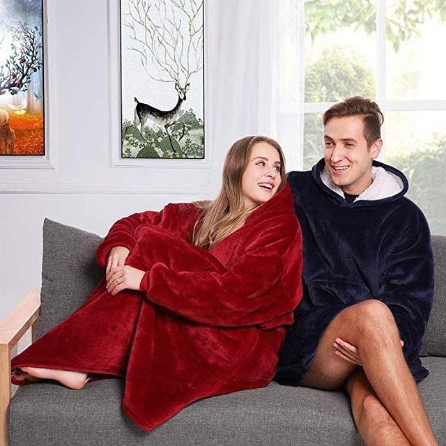 Model wearing an oversized wearable blanket sweatshirt with a hood, looking comfortable and warm