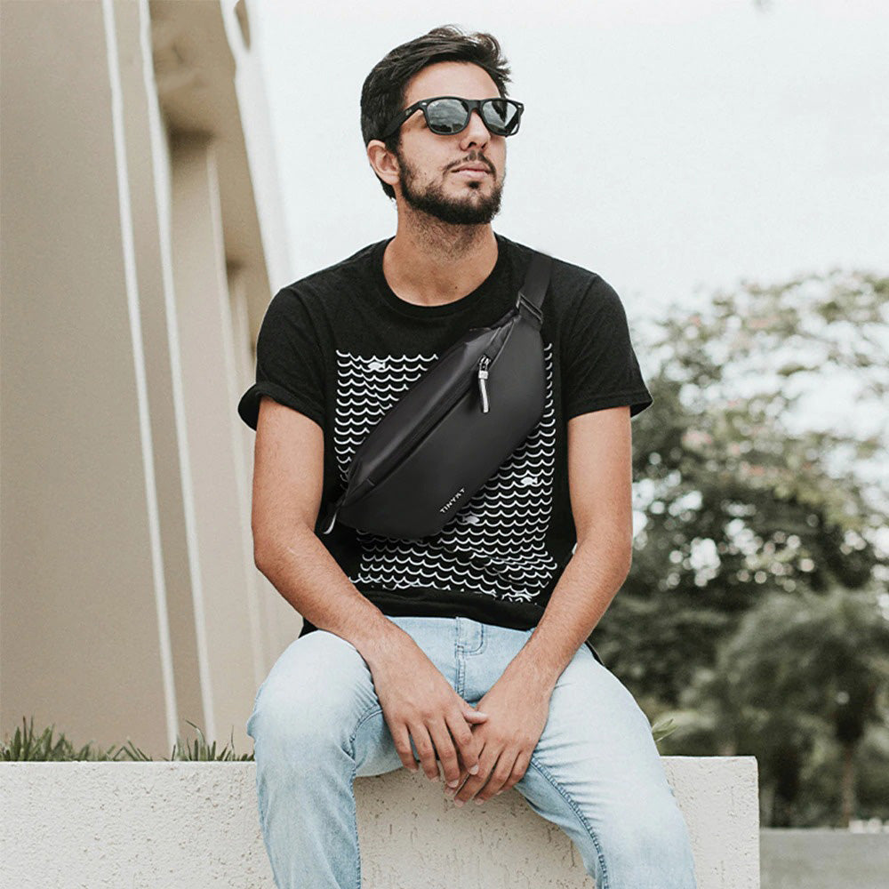 Stylish water-resistant fanny pack worn by a traveler. Secure multi-pocket waist bag for essentials during trips.