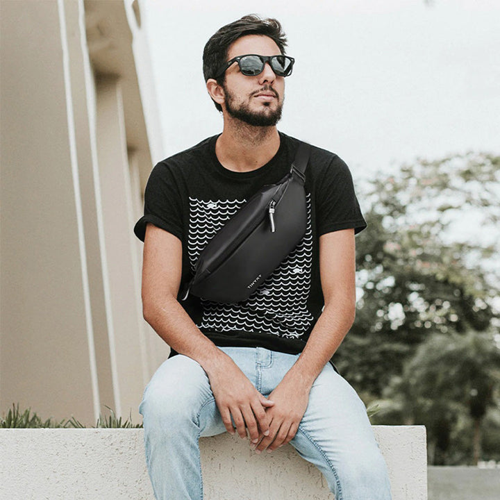 Stylish water-resistant fanny pack worn by a traveler. Secure multi-pocket waist bag for essentials during trips.