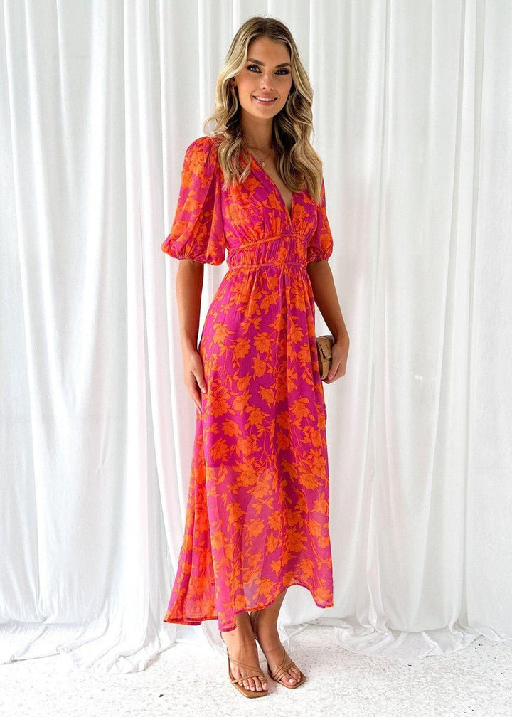 Women's flowing pink orange floral maxi dress with V-neck and flutter sleeves, ideal for a stylish summer vacation.