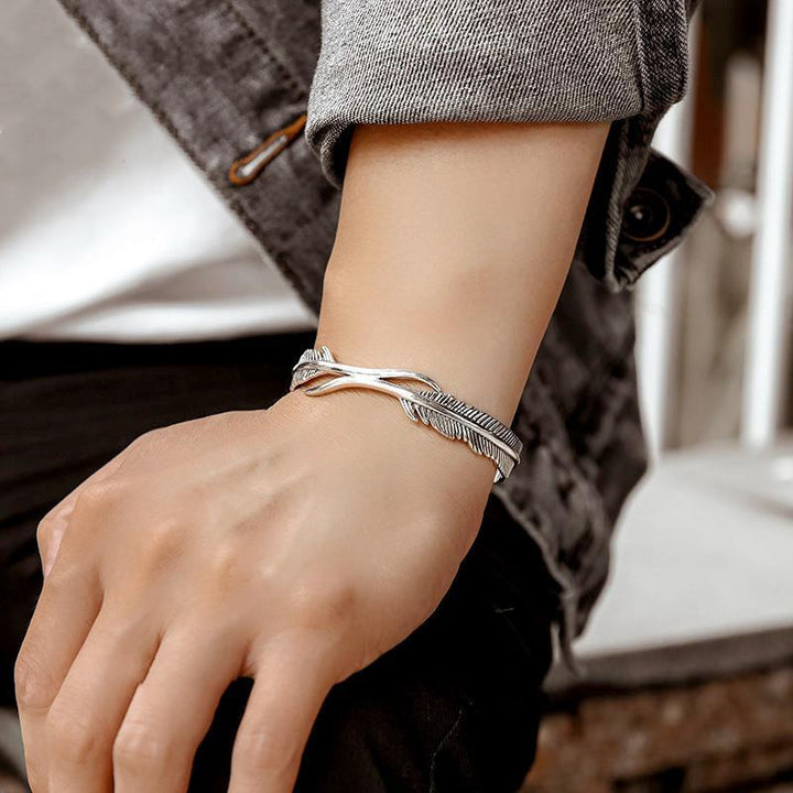 Close-up of a women's silver tone feather charm on an adjustable bracelet, angelic design