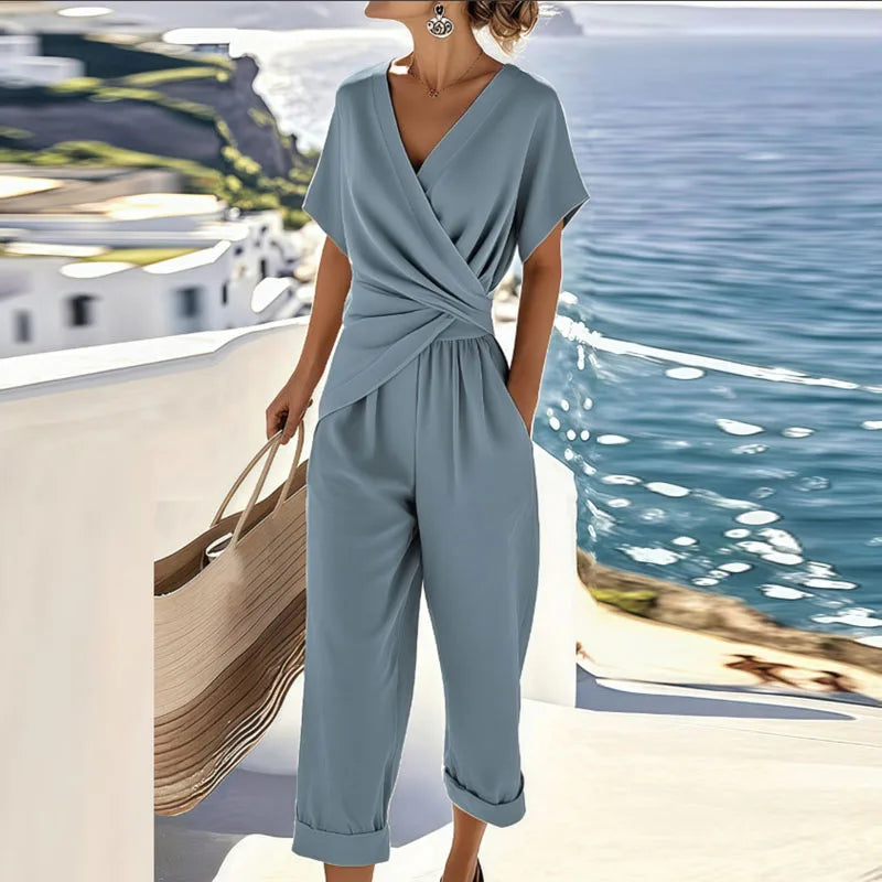 Stylish women's blue wrap jumpsuit with V-neck, short sleeves & tie waist, ideal for vacation or casual summer.