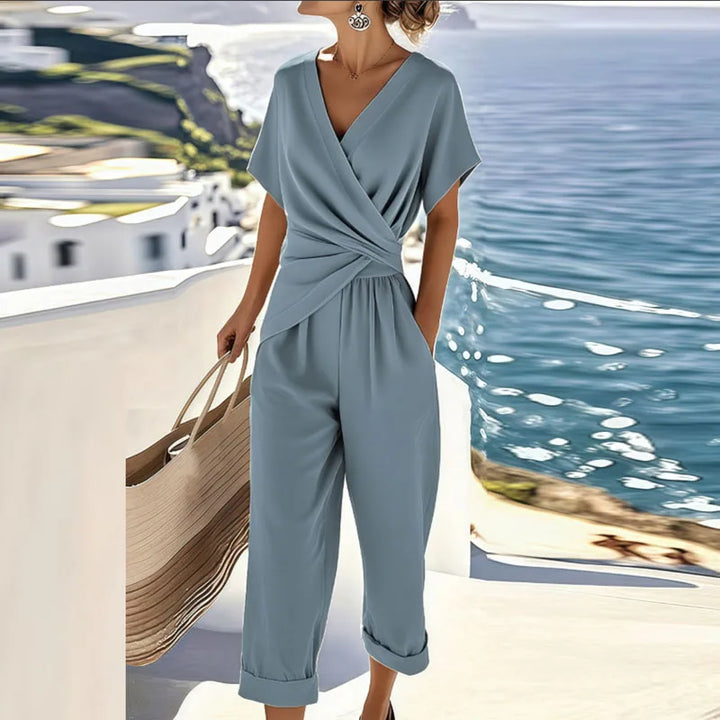 Stylish women's blue wrap jumpsuit with V-neck, short sleeves & tie waist, ideal for vacation or casual summer.