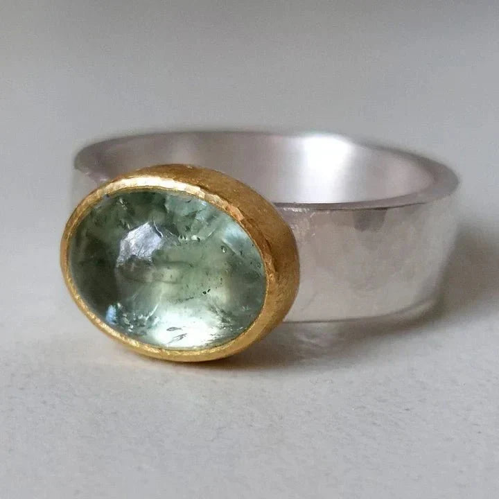 Women's aquamarine cocktail ring with a striking gold bezel setting on a wide silver band. Mixed-metal gemstone statement ring.