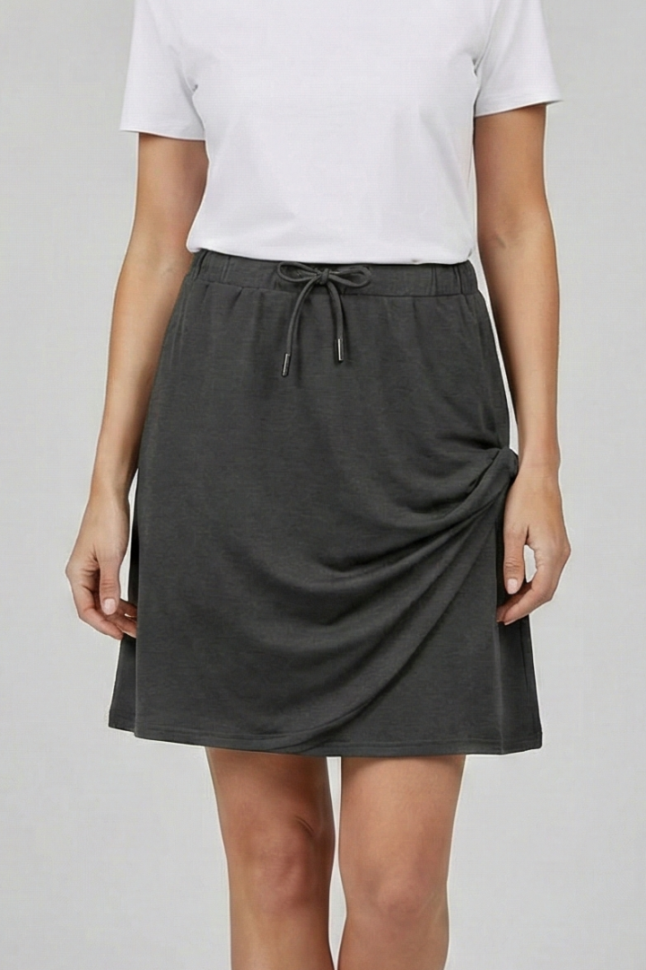 Model wearing a women's black drawstring skirt with built-in shorts for active outdoor style.