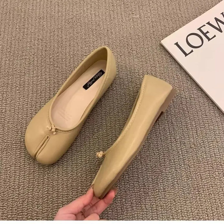 Women's minimalist black faux leather flats with a distinct split toe.