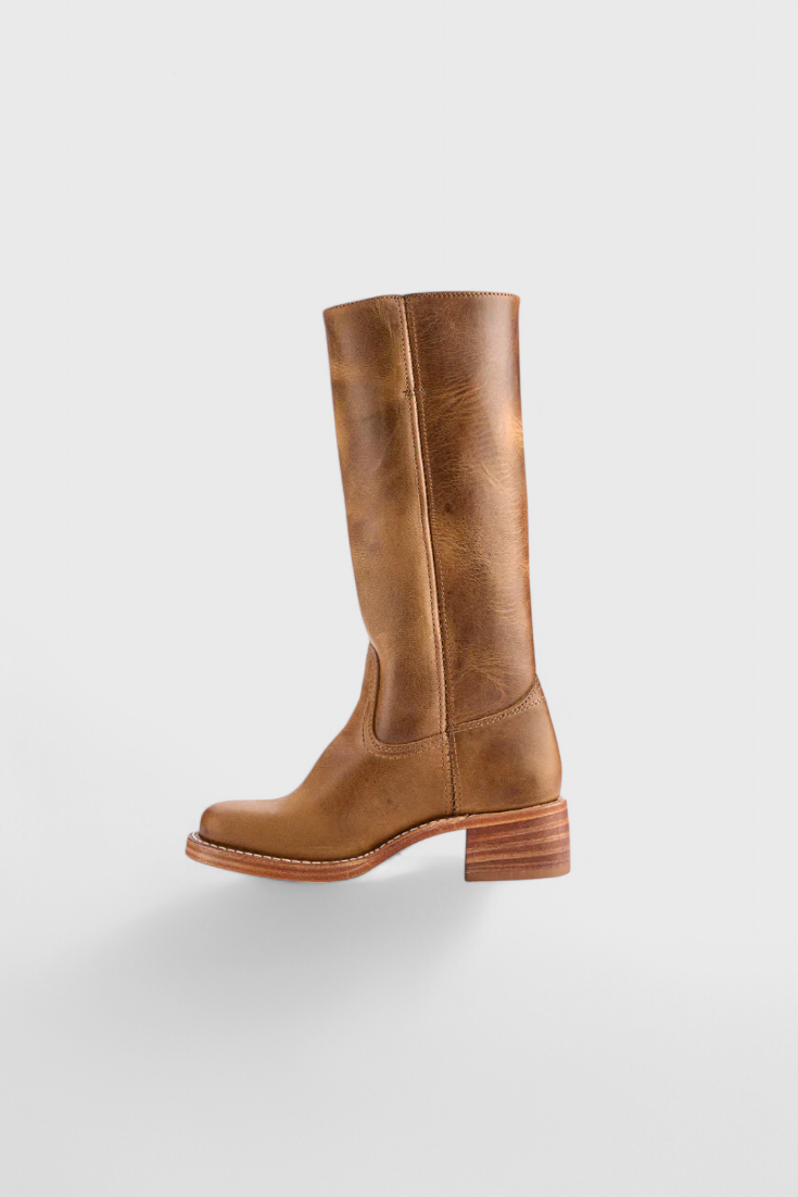 Close-up of women's knee-high heeled leather boots, showing the texture and sheen of the material.