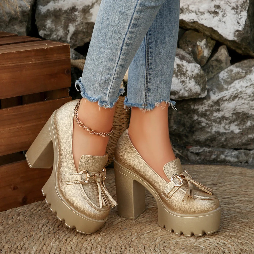 Overhead view of women's patent leather platform loafers with prominent tassel accents.
