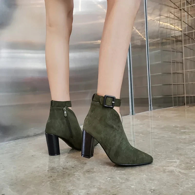 Front view of women's pointed-toe ankle boots, black, with unique buckle embellishments