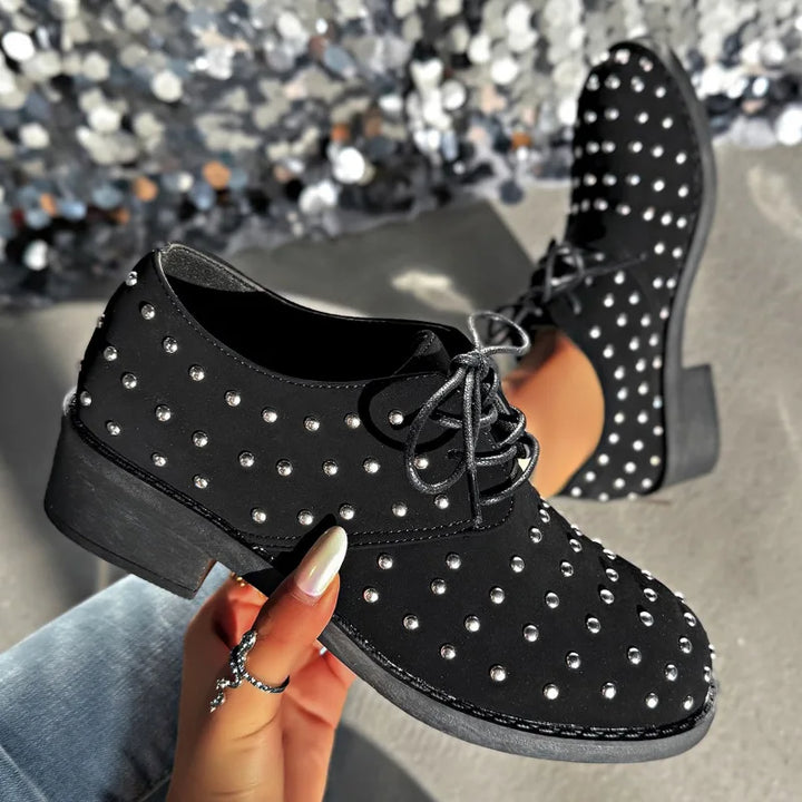 Pair of women's black studded lace-up oxford footwear, ideal dress shoes for fashion-conscious comfort.