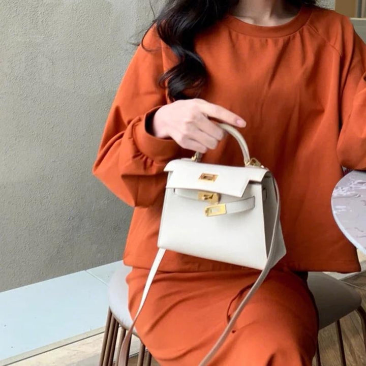 Stylish black women's crossbody bag. Top handle, shoulder strap & elegant turn lock. Versatile, structured fashion handbag.